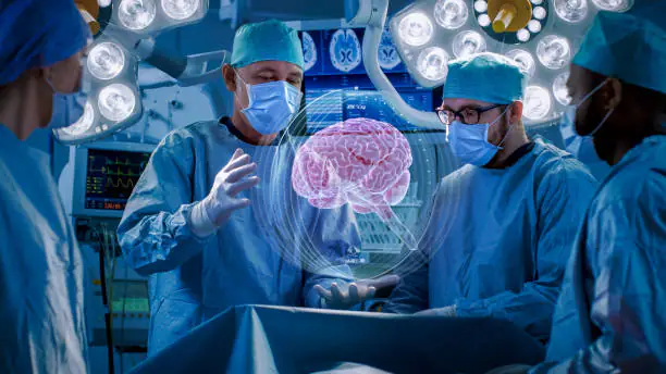 A group of surgeons in full sterile attire and masks operate in a modern, well-lit operating room, viewing a holographic or digital projection of a human brain above the surgical table.