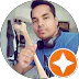 Circular-cropped profile photo of a man in a blue t-shirt holding a bone model, wearing headphones around his neck, with a white star badge in the corner.