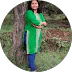 Circular-cropped photo of a woman standing outdoors in front of a tree, wearing a green kurta and blue jeans.